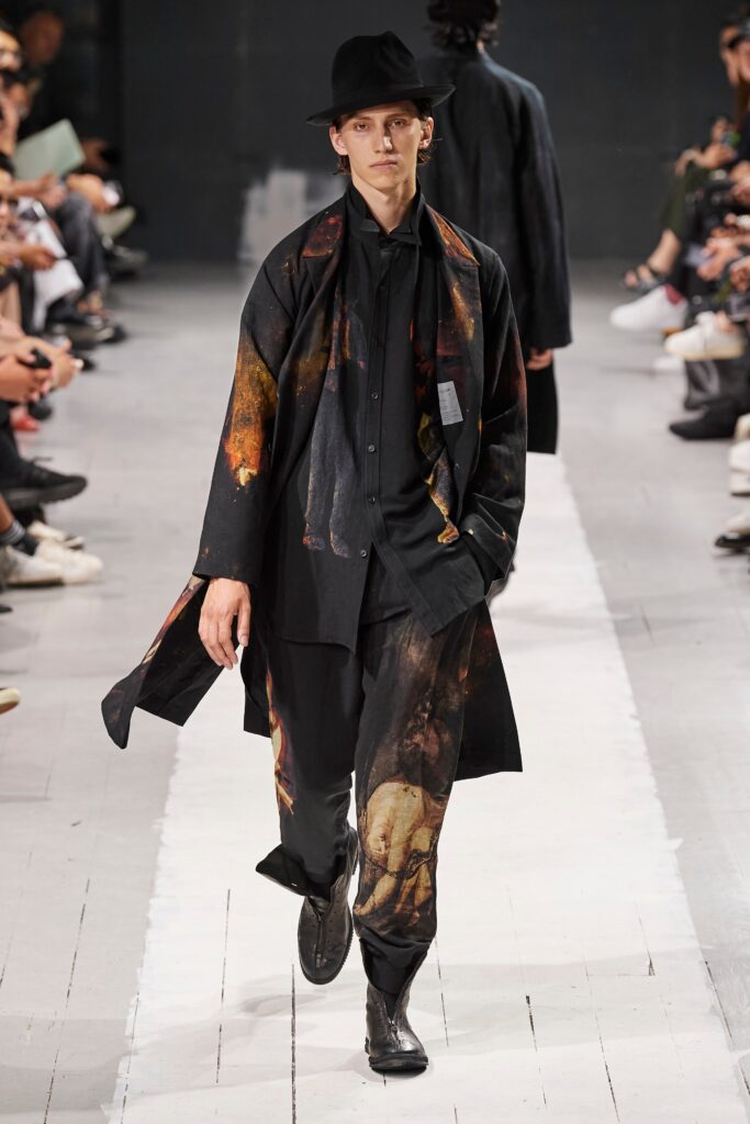 A relaxed black coat with a printed design, paired with matching pants.