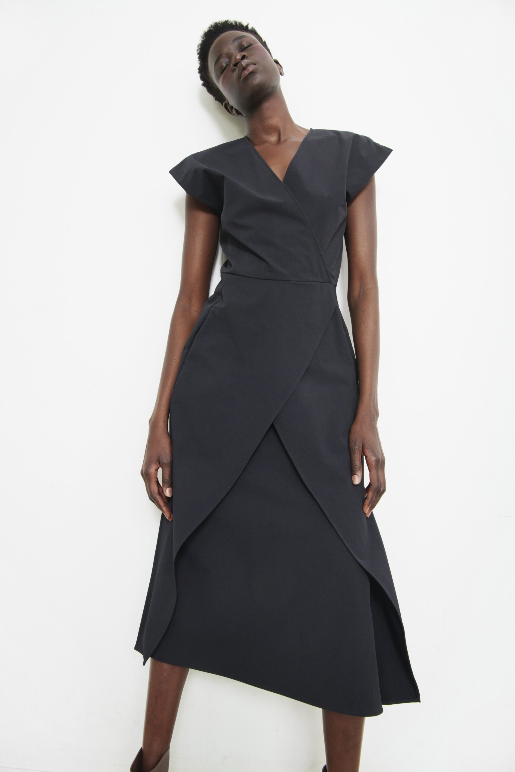 A fitted black dress with a V-neckline and asymmetric design details.