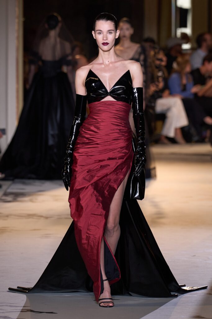 A fitted black and red sleeveless dress with a V-neckline and a high slit.