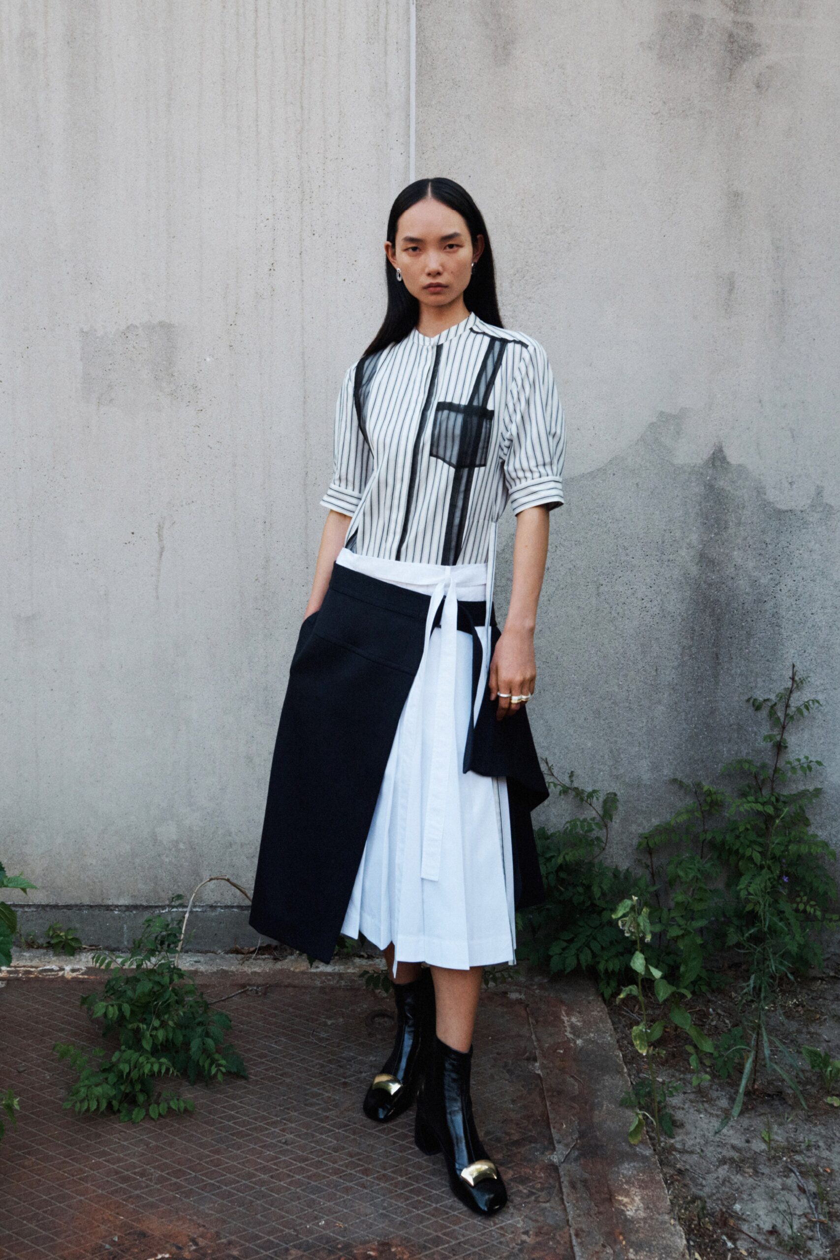 A fitted black and white striped dress with a collared short-sleeve design and asymmetric detailing.