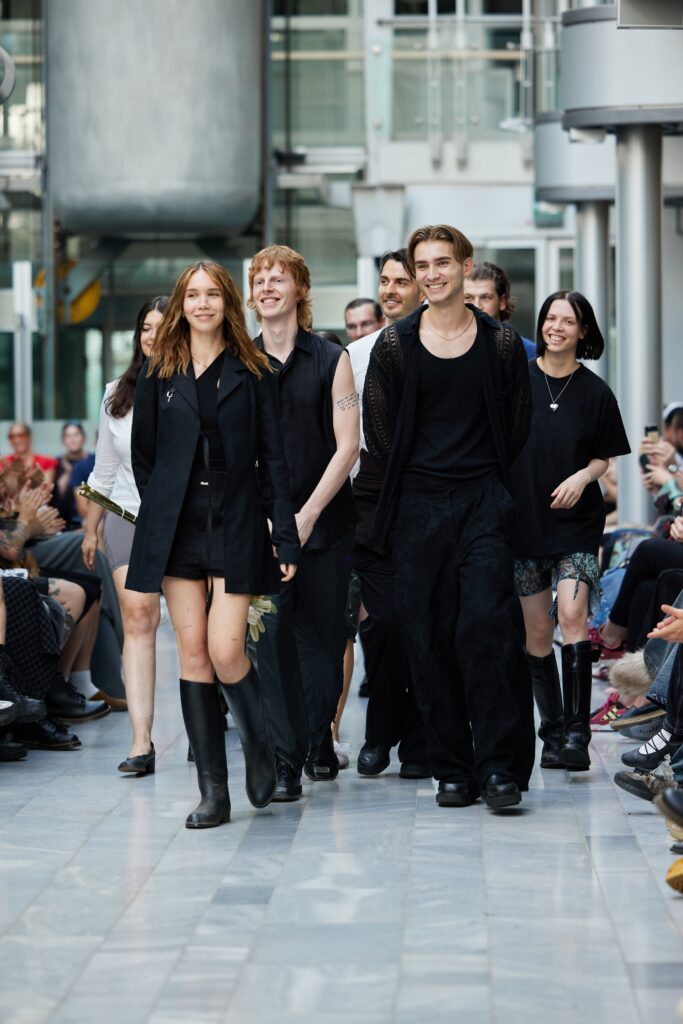 A fitted black mini dress with a sleeveless design and V-neckline.
