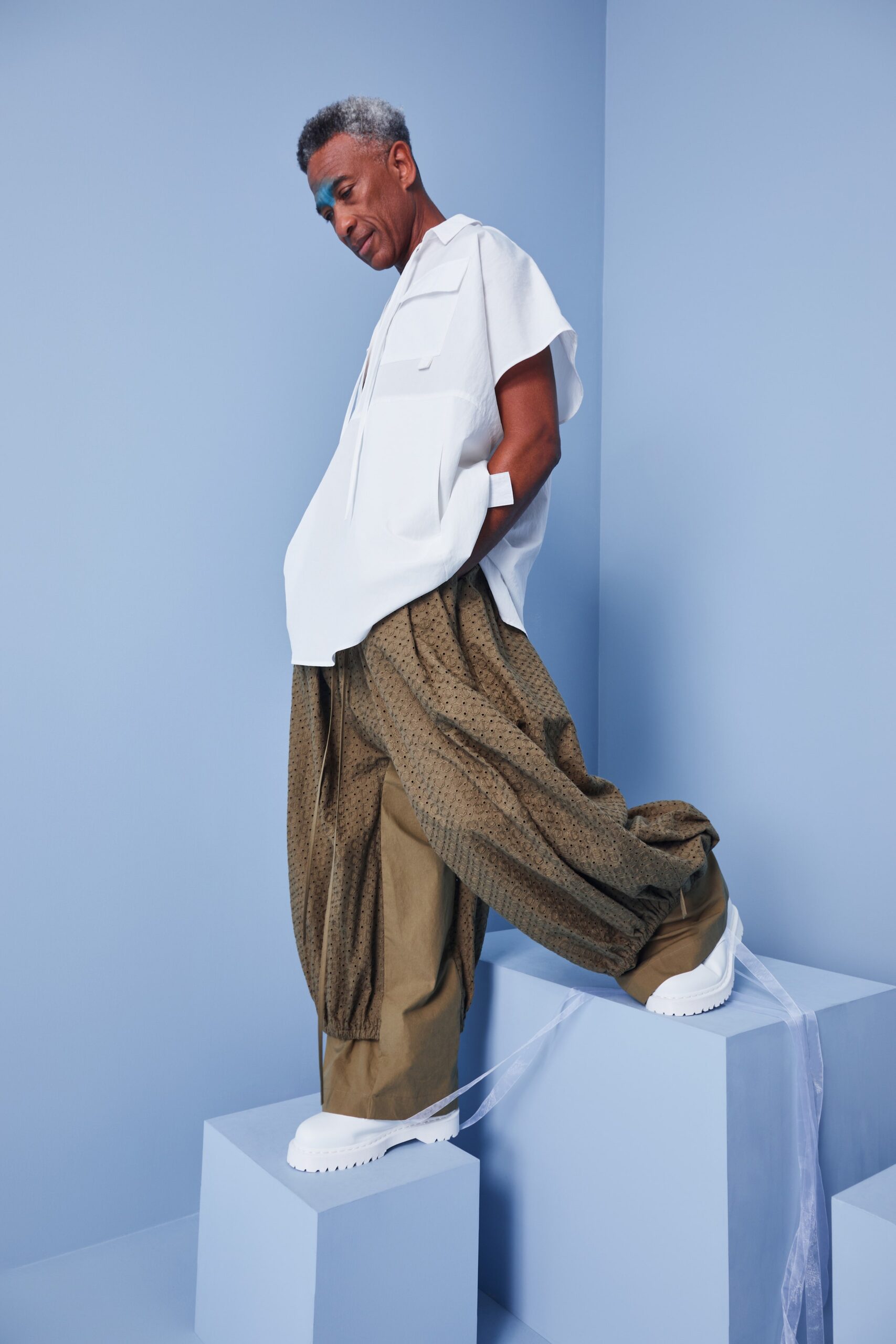 This ensemble features a relaxed white top with a collared neckline and short sleeves, paired with wide-leg pants that showcase a unique pleated texture. The combination creates an effortless silhouette that balances comfort and style, making a bold statement in a contemporary palette.