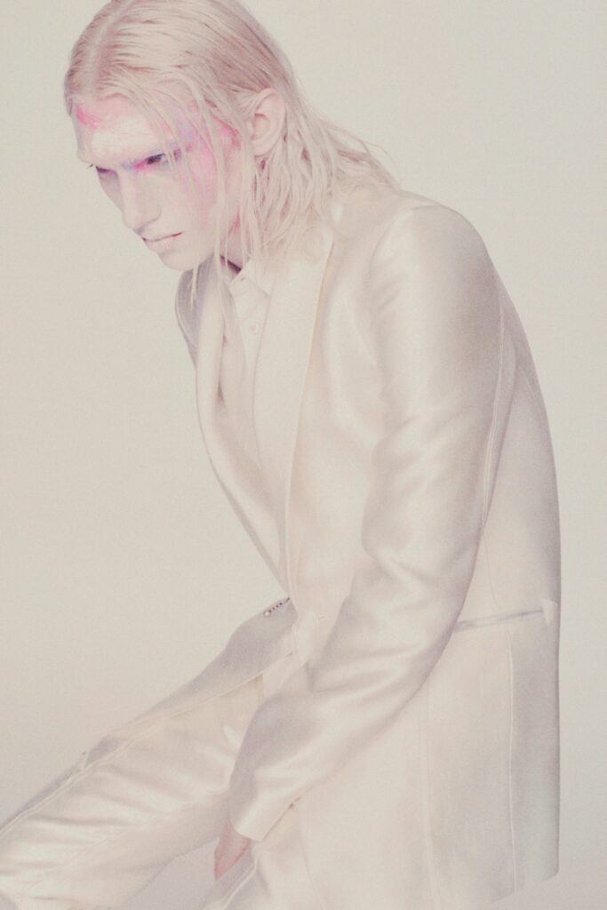 A fitted white silk suit with a structured design and long sleeves.
