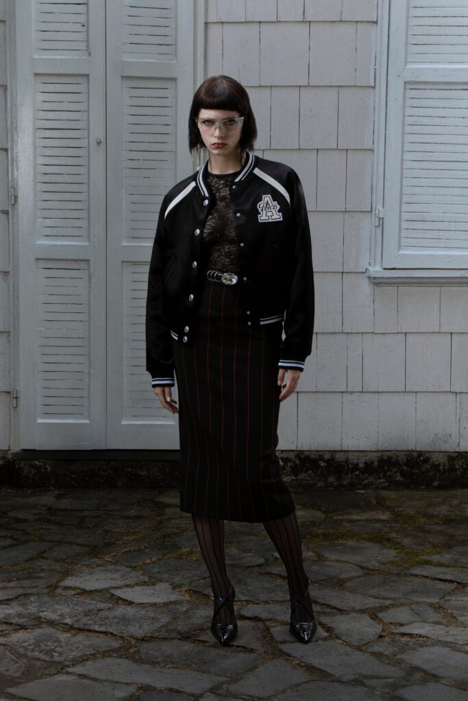 A fitted black jacket with long sleeves paired with a fitted striped skirt.