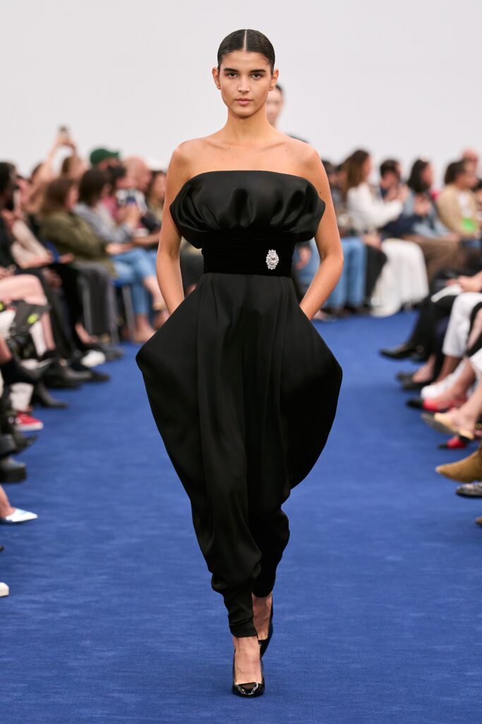 A fitted black silk strapless dress with an asymmetric silhouette and elegant design.