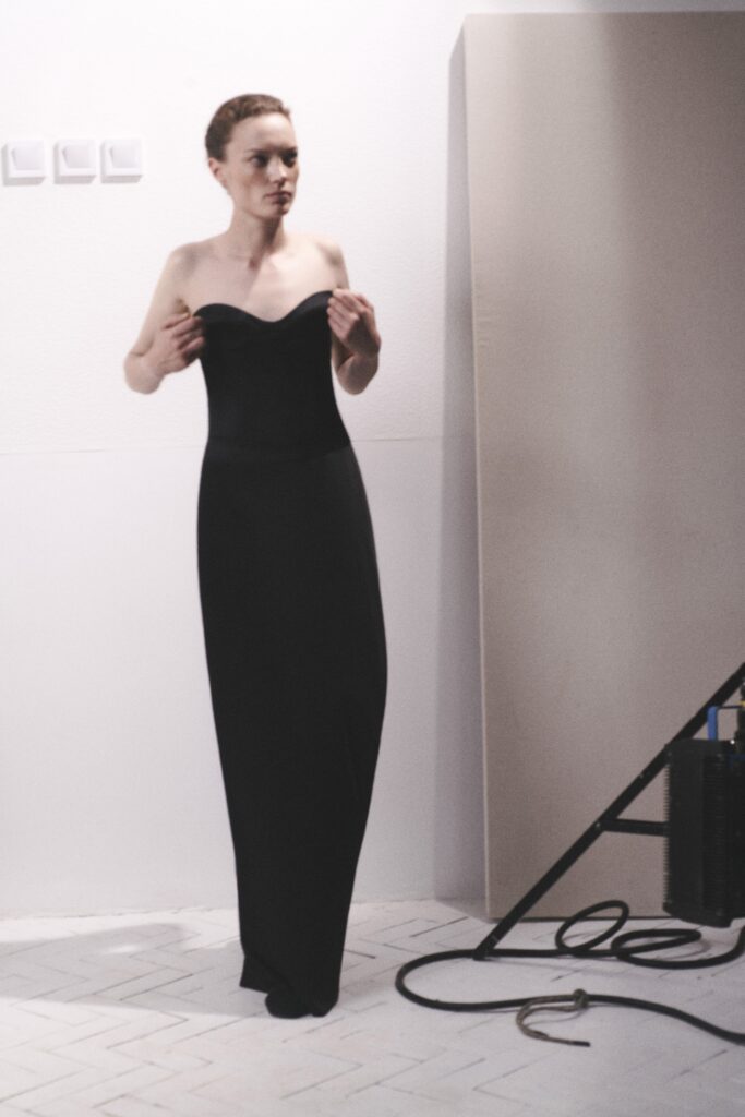 A fitted black silk dress with a strapless design and straight-leg silhouette.