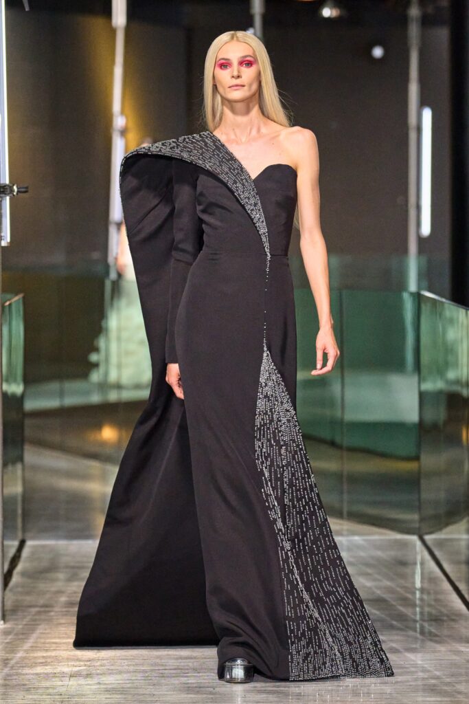 A fitted black silk sleeveless dress with an asymmetric design and V-neckline.