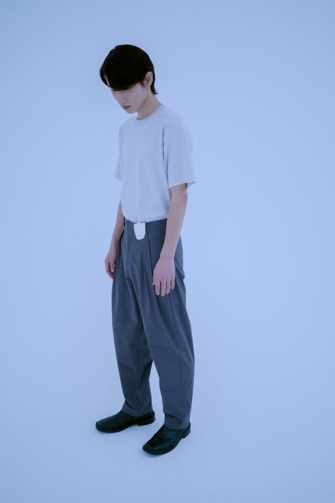 A relaxed white cotton short-sleeve shirt paired with high-waisted gray straight-leg pants.