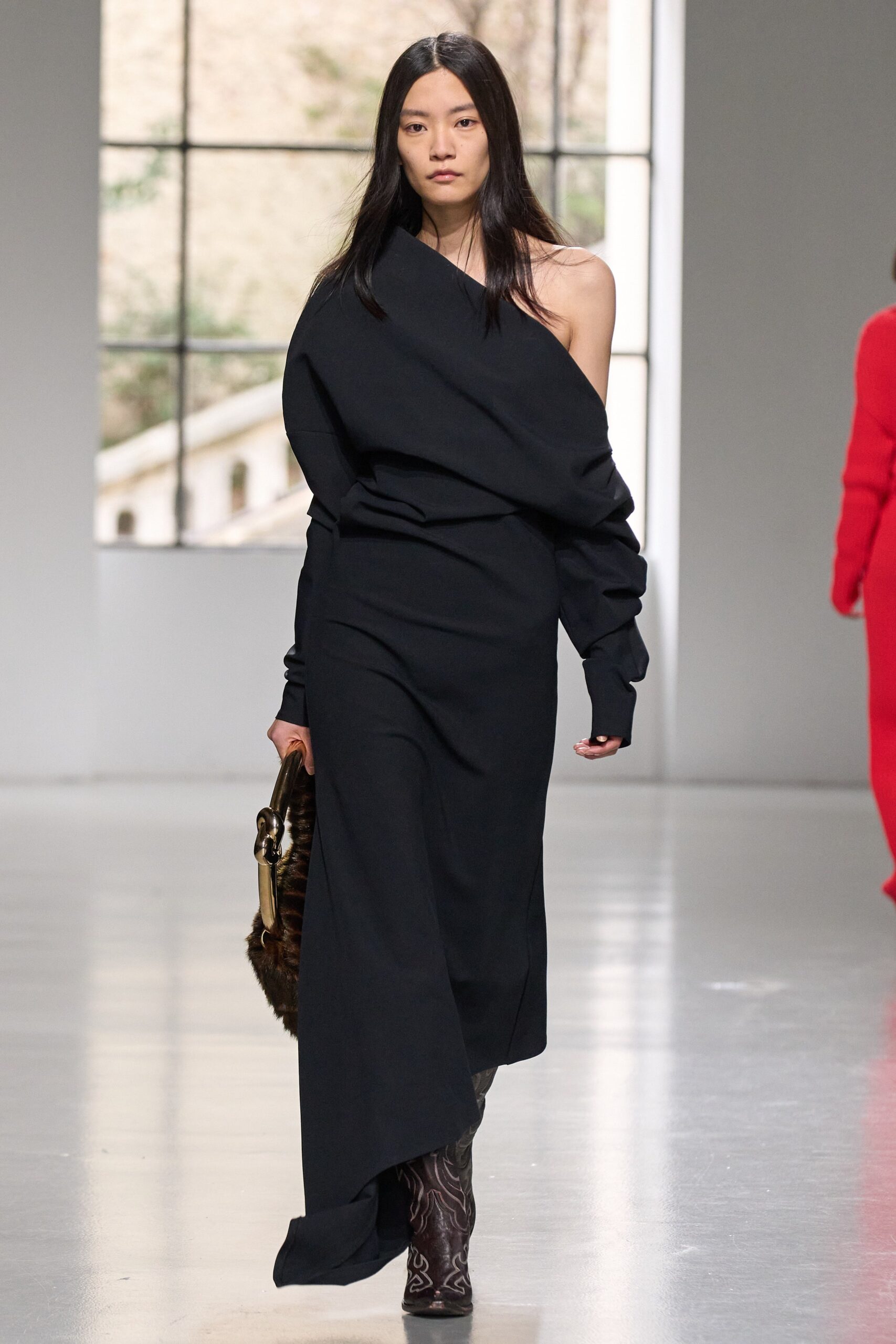A relaxed black dress with long sleeves and an off-shoulder design featuring an asymmetric silhouette.