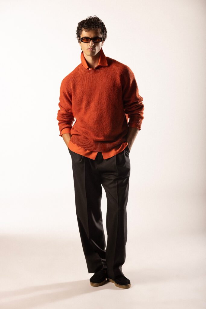 A relaxed orange long-sleeve sweater with a collared neckline paired with black pants.