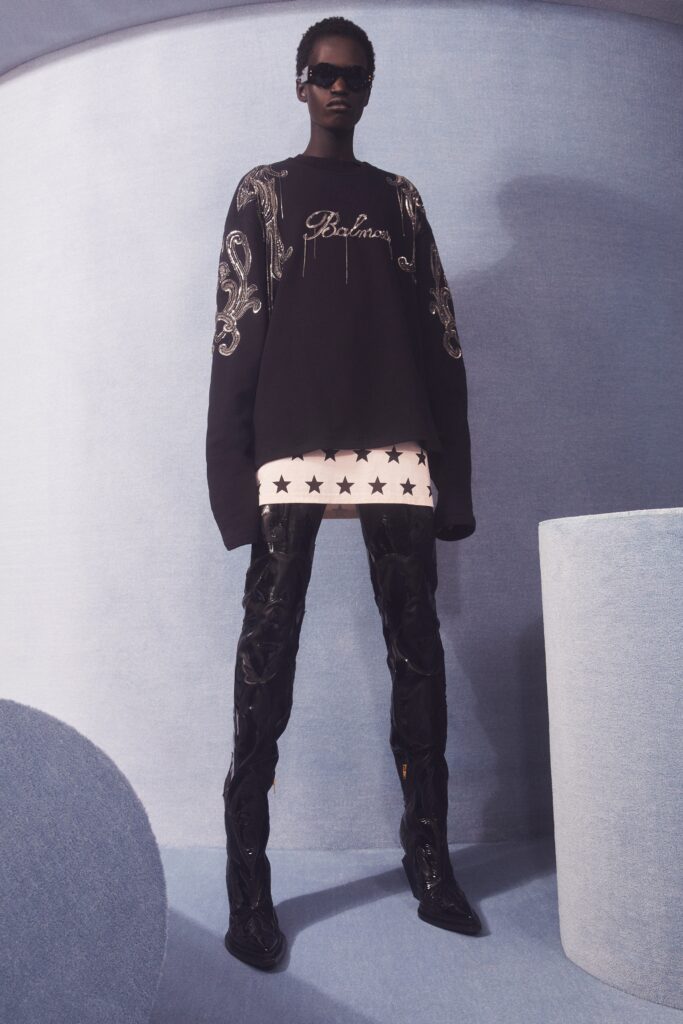 An oversized black sweater paired with high-waisted leather pants, featuring a stylish graphic design.