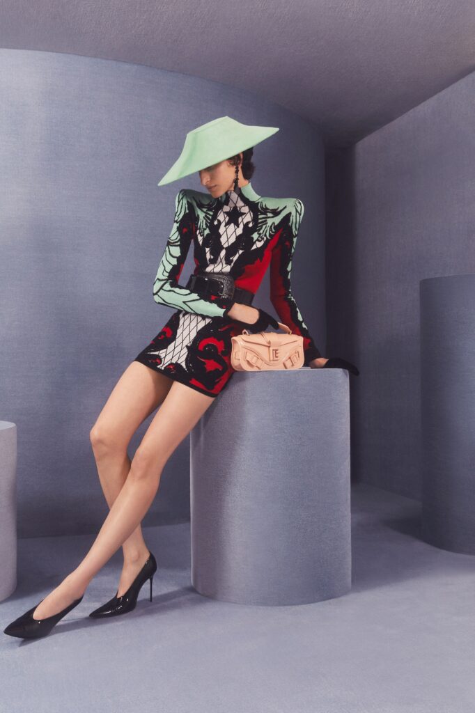 A fitted dress featuring long sleeves, a high neckline, and an asymmetric printed design.