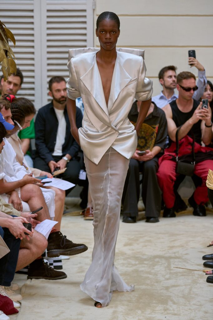 A fitted silver silk dress with a V-neckline and asymmetric design details.