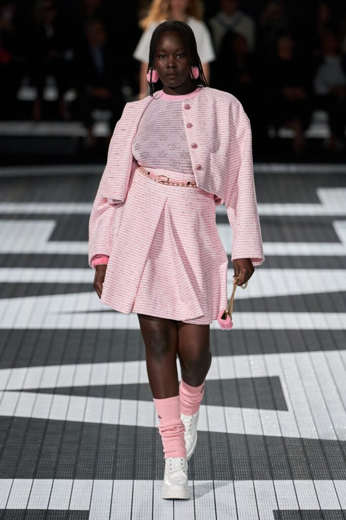 A fitted pink skirt paired with a matching long-sleeve jacket featuring a pleated design.