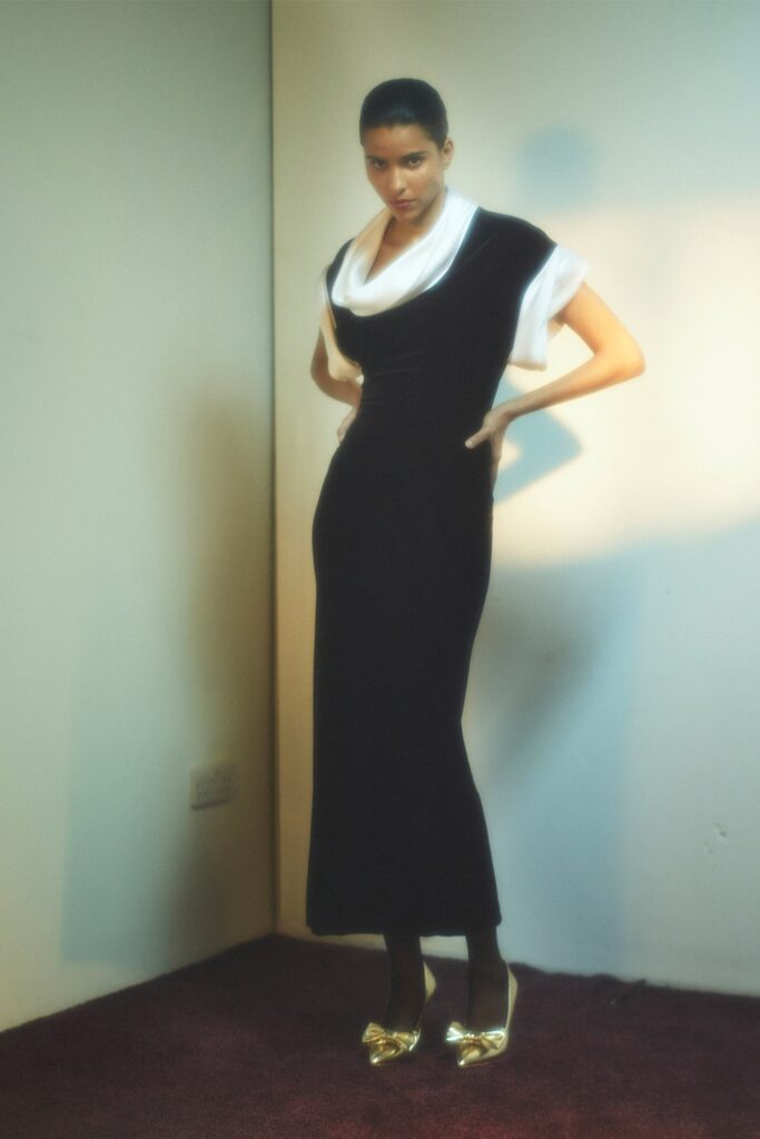 A fitted black velvet dress with a V-neckline and a straight-leg silhouette.