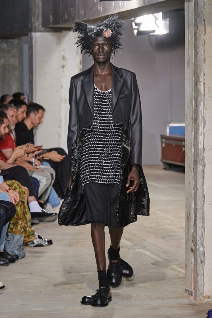 A fitted black dress layered with a long-sleeve coat featuring a V-neckline.