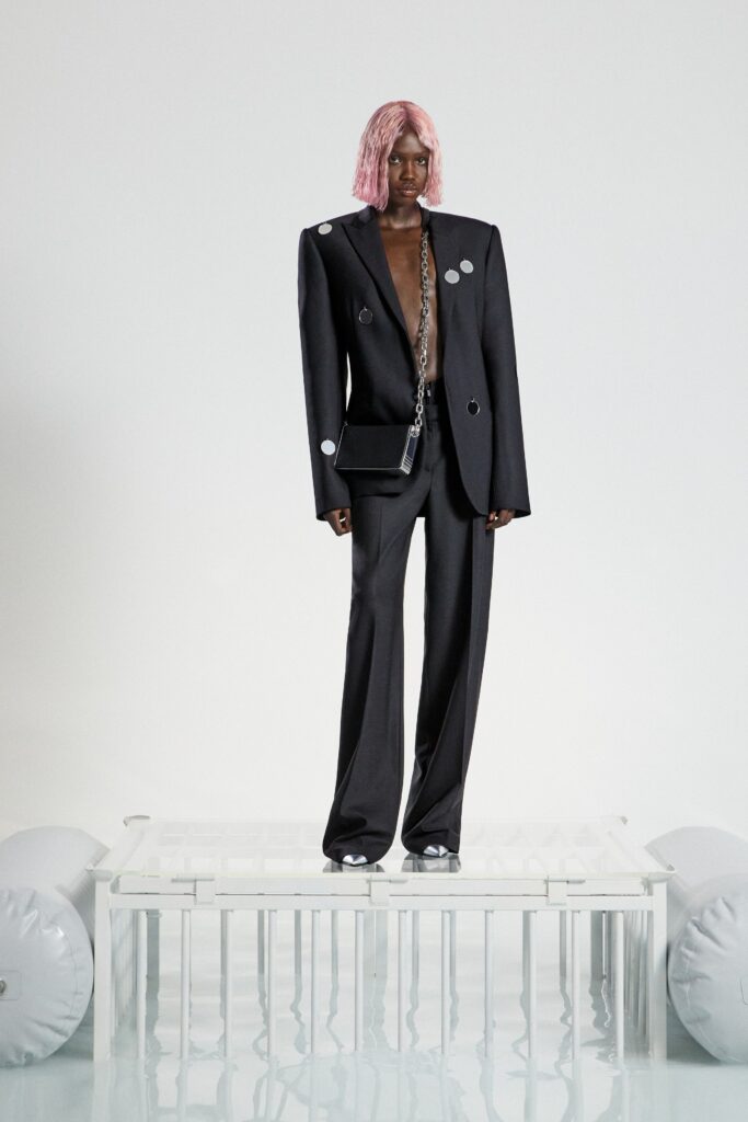 A tailored black silk suit with long sleeves and an asymmetric design featuring button details.