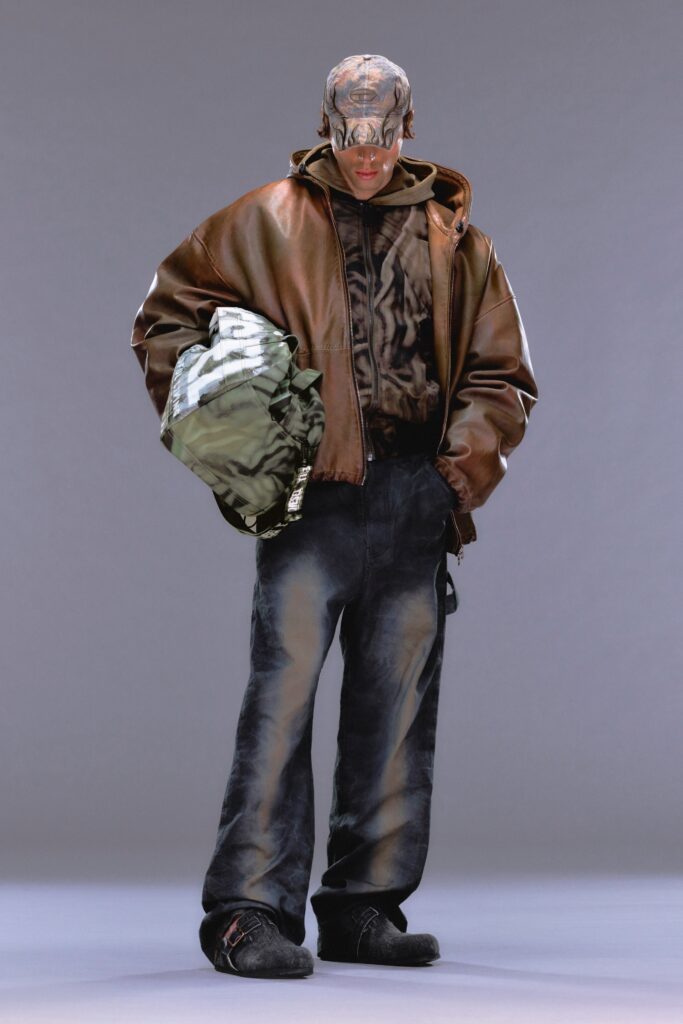 A relaxed brown leather jacket paired with black denim pants featuring a printed top.