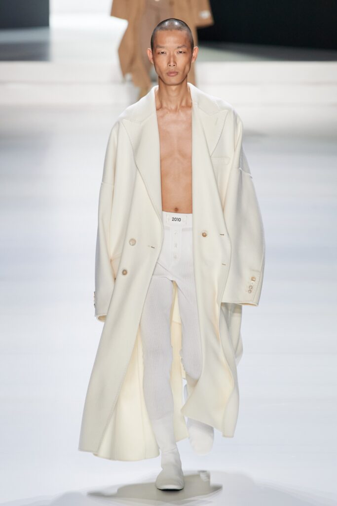 An oversized white wool coat with long sleeves and a collared design featuring button details.