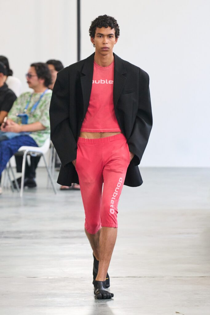 An oversized black jacket paired with fitted red pants featuring a printed design.