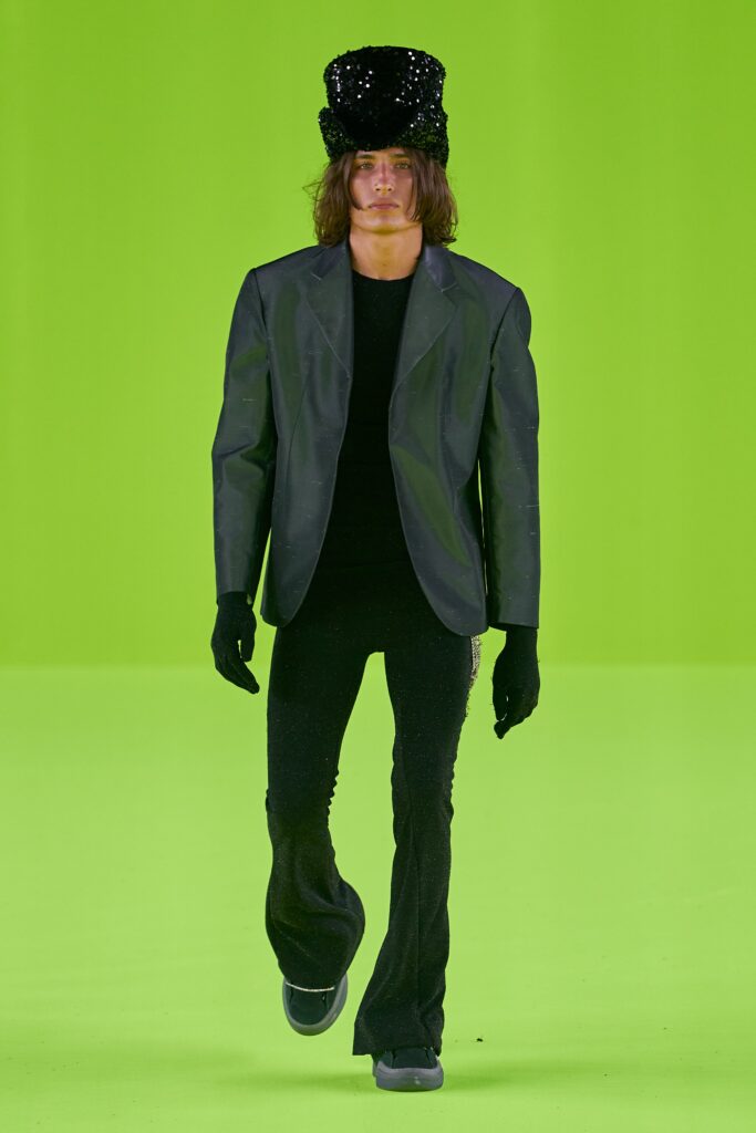 A fitted black jacket with long sleeves paired with flared black pants.