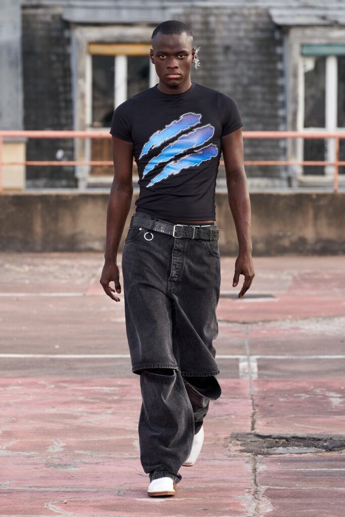 A relaxed black t-shirt with a blue graphic and wide-leg denim pants.