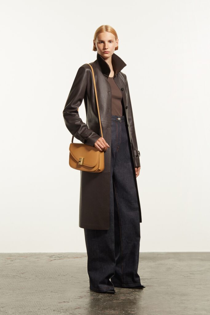A relaxed black leather coat paired with wide-leg blue denim pants.