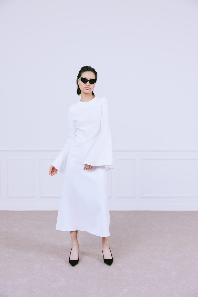 A fitted white long-sleeve dress with a high neckline and straight-leg silhouette.