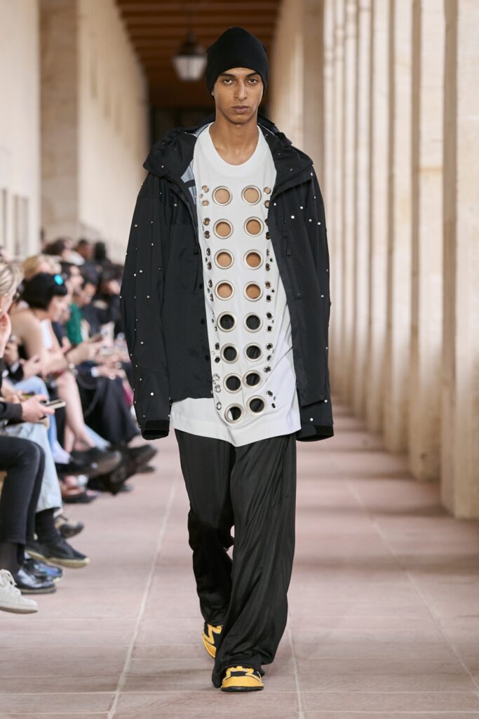 A relaxed black jacket layered over a printed white t-shirt with long sleeves.