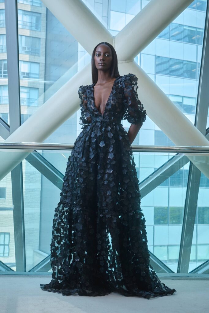 A fitted black silk dress with long sleeves and a V-neckline featuring a layered design.