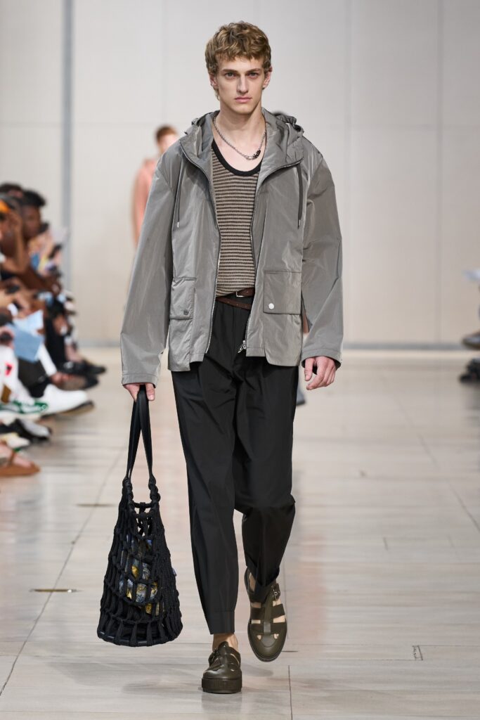 A relaxed gray jacket with a collared neckline paired with black pants featuring a striped design.
