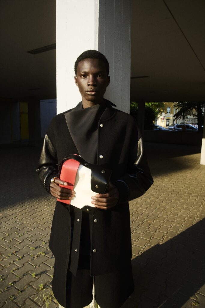 A relaxed black wool coat with long sleeves and an asymmetric design detail.