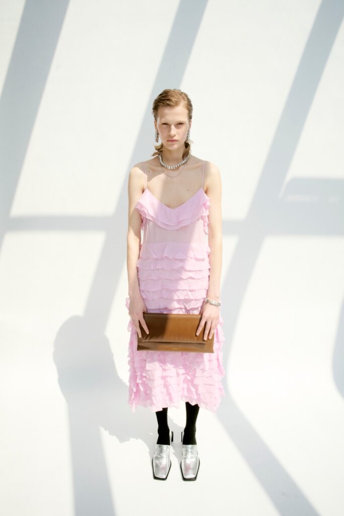 A fitted pink silk sleeveless dress with a V-neckline and ruffled design.