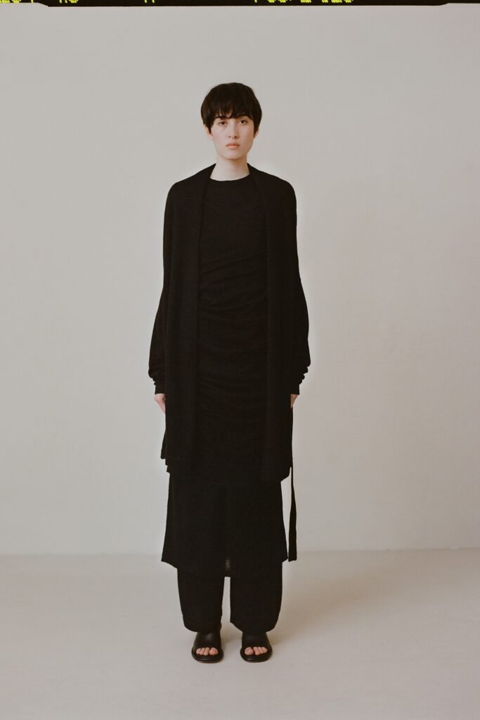 A relaxed black dress layered with a long-sleeve coat featuring a V-neckline.