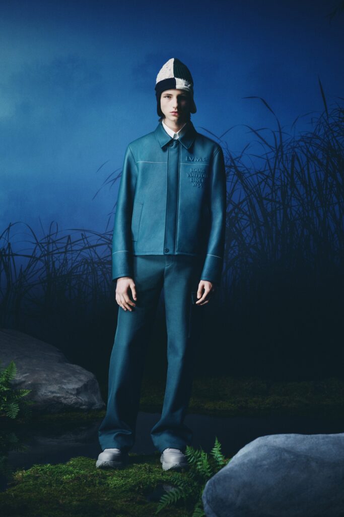 A fitted blue leather jacket with long sleeves and collared design paired with straight-leg pants.