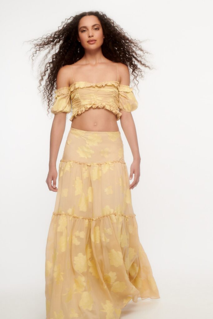A fitted yellow floral crop-top and tiered skirt with an off-shoulder design.