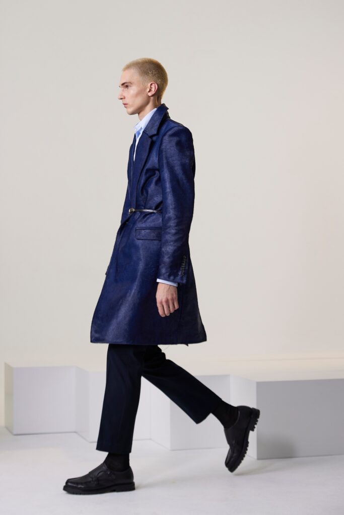 A fitted blue leather coat with a collared neckline and belted detail.