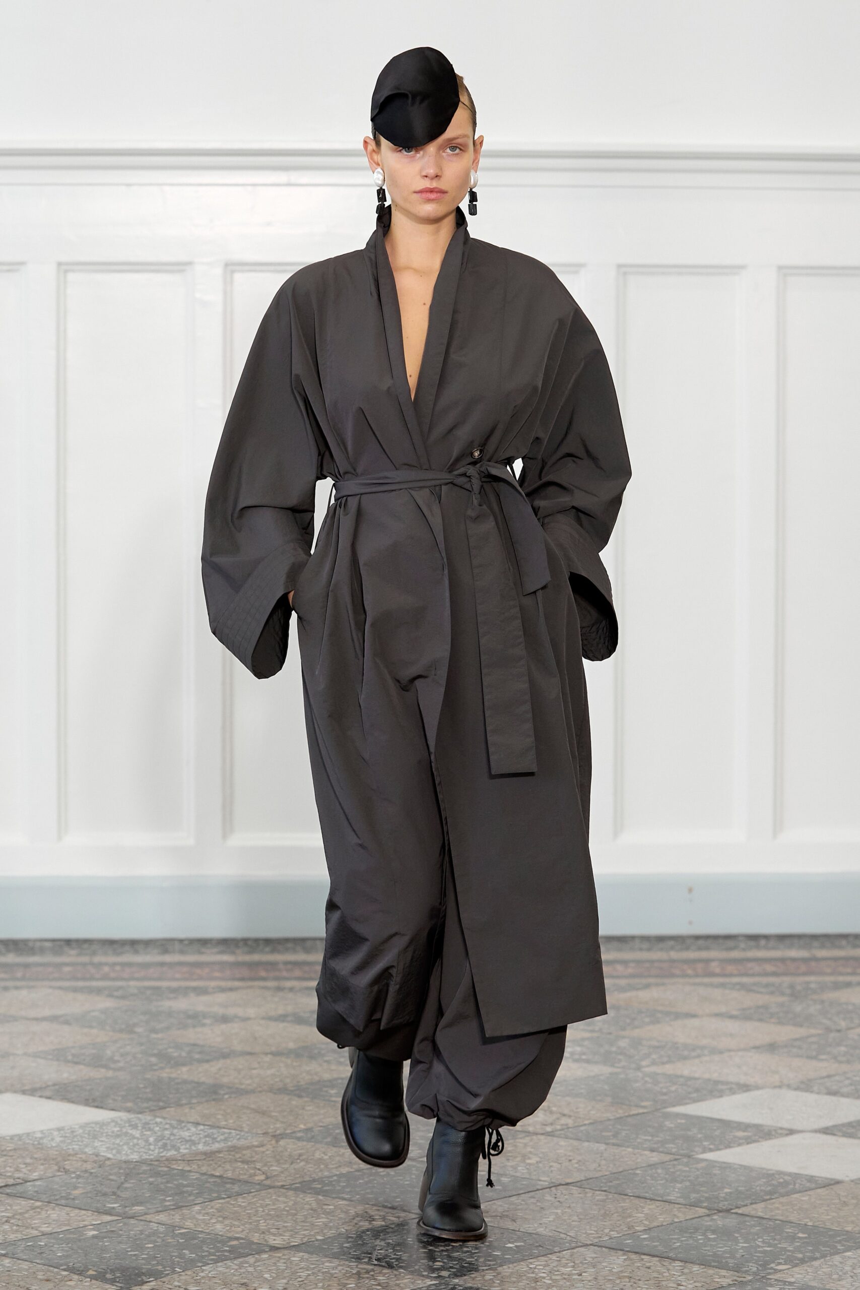A relaxed black coat with a V-neck and belted design, paired with matching pants.