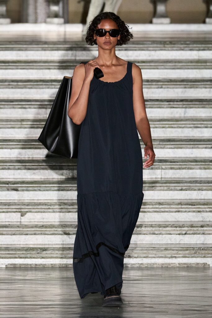 A relaxed black cotton sleeveless dress with a high neckline and tiered design.