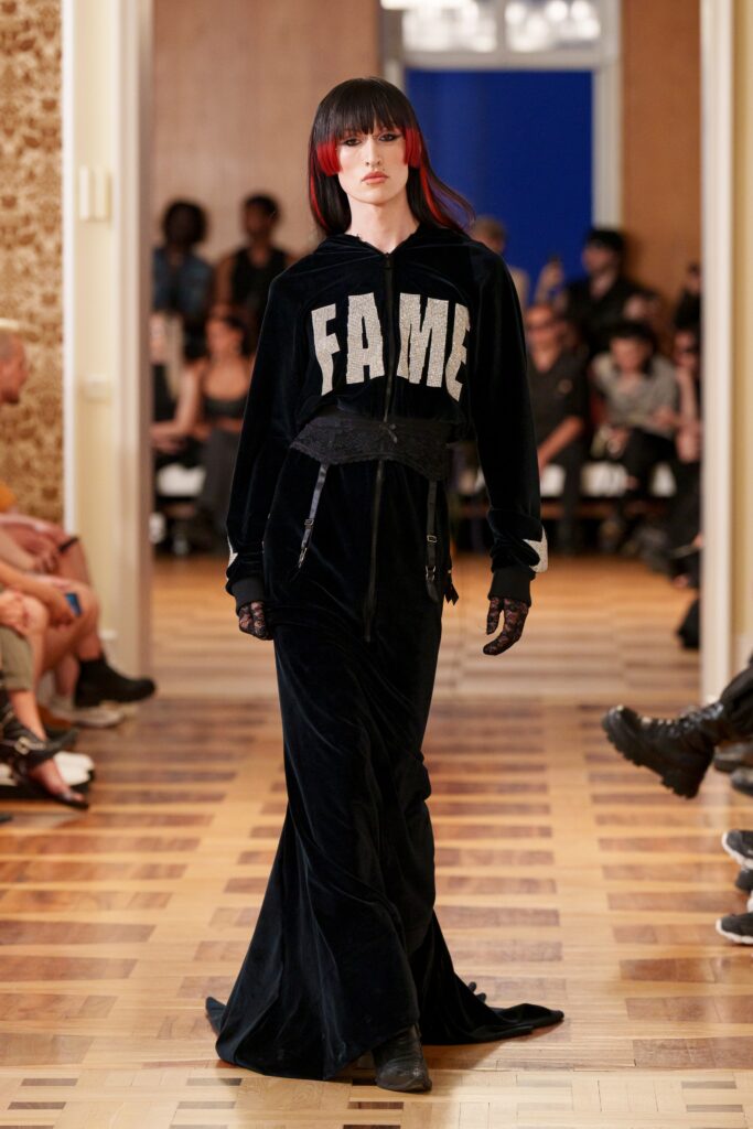A fitted black velvet dress with a hoodie and long sleeves, featuring a bold graphic.