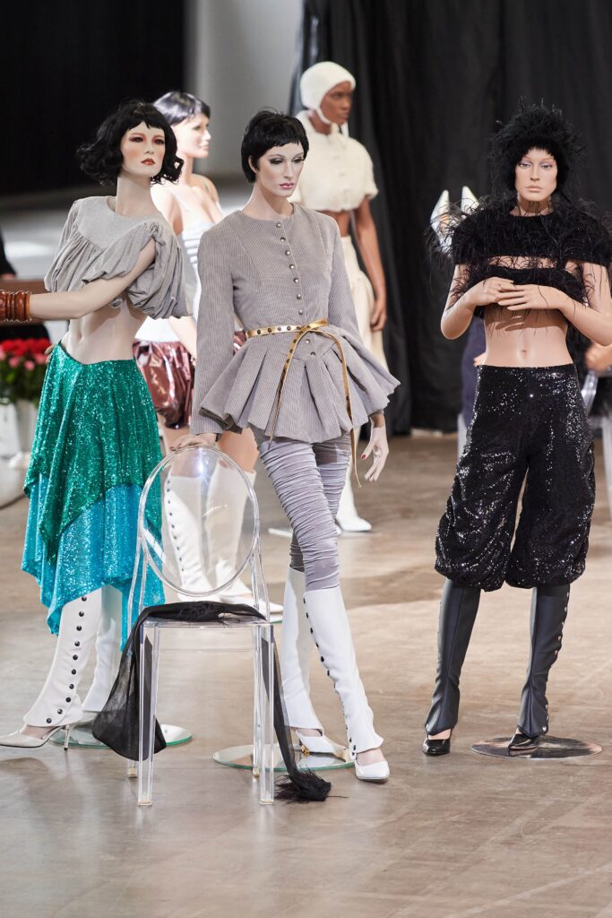A fitted gray blouse with a collared neckline and asymmetric design paired with black pants.