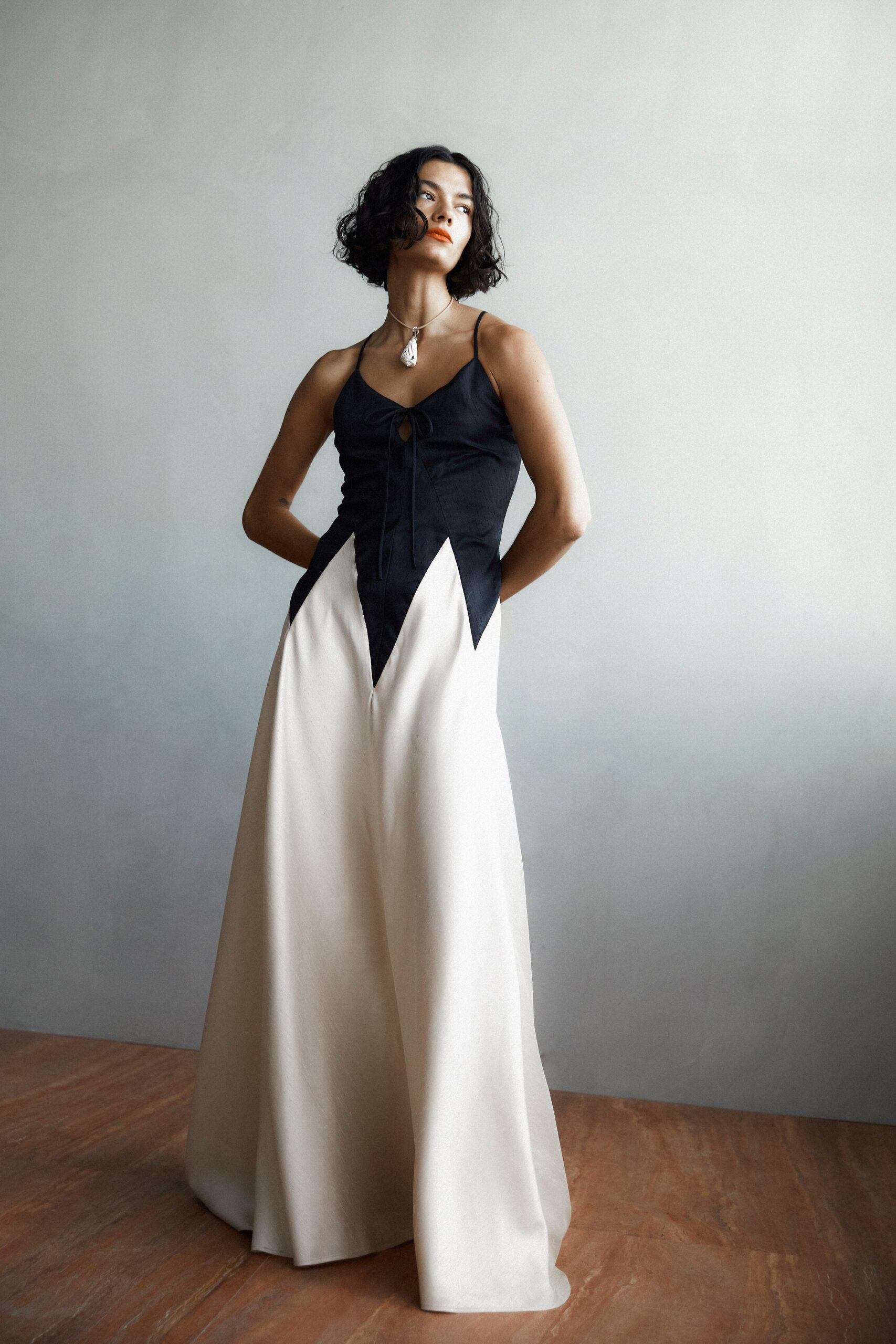 A fitted black and white sleeveless dress with a V-neckline and asymmetric design.