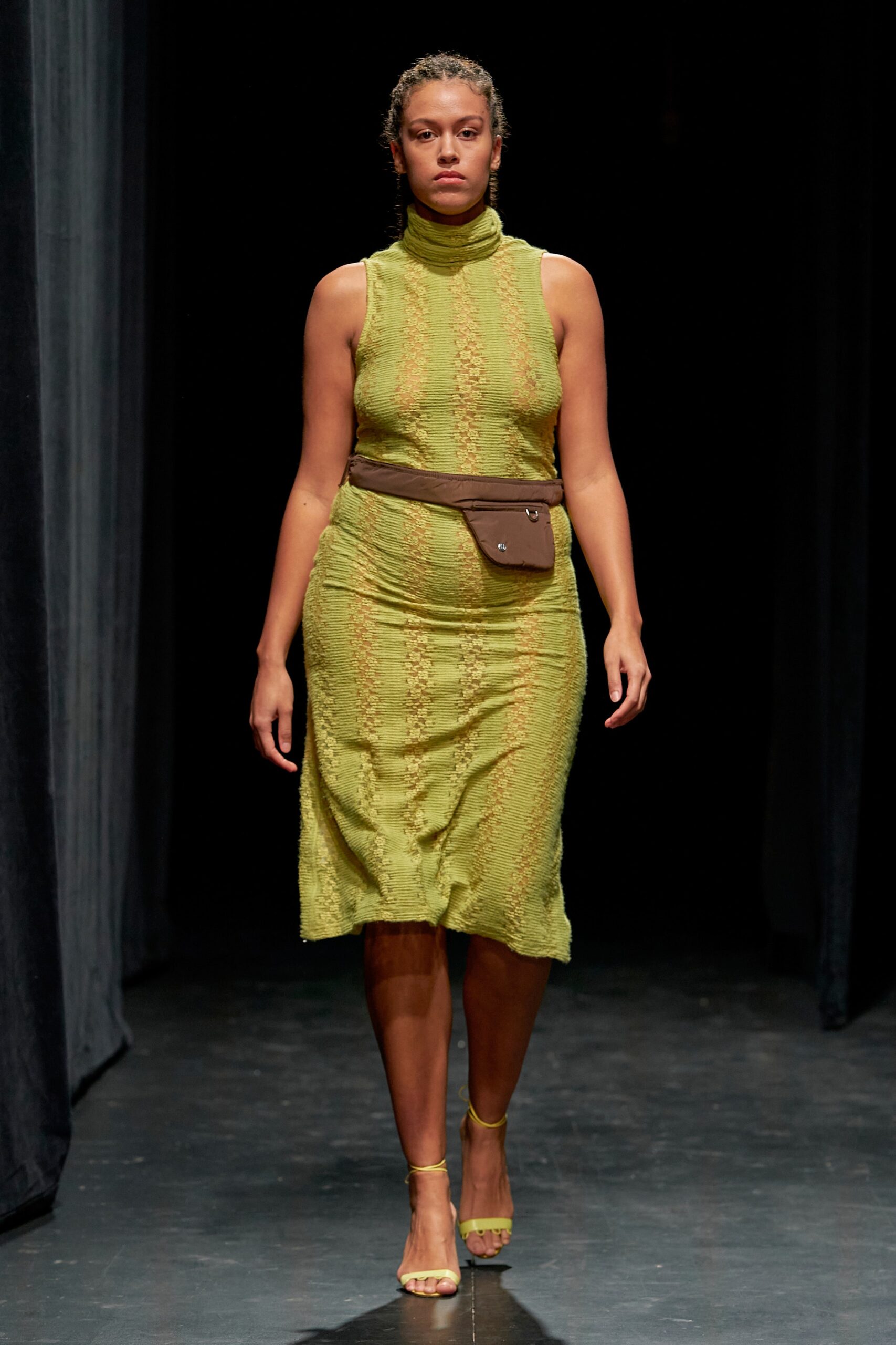 A fitted green knit dress with a high neckline and tiered design.