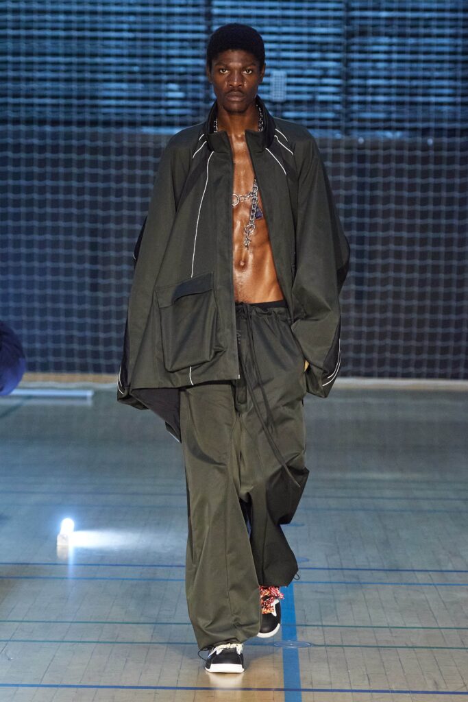 A relaxed green jacket with long sleeves paired with loose-fitting pants featuring an asymmetric design.
