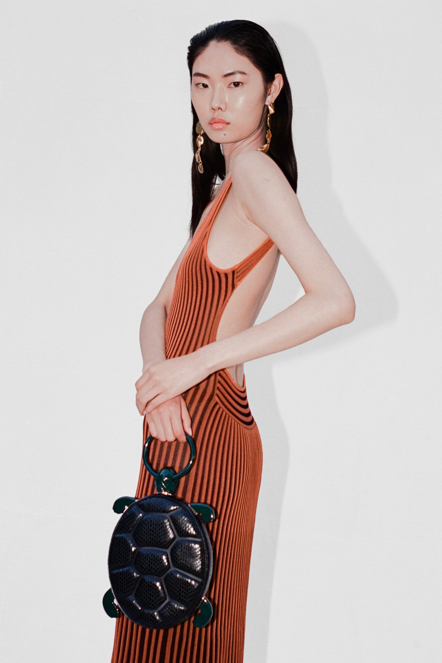 A fitted orange striped dress with a sleeveless design and high neckline.
