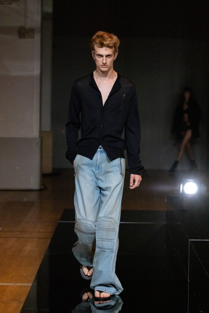 A relaxed black long-sleeve shirt paired with relaxed blue denim pants.