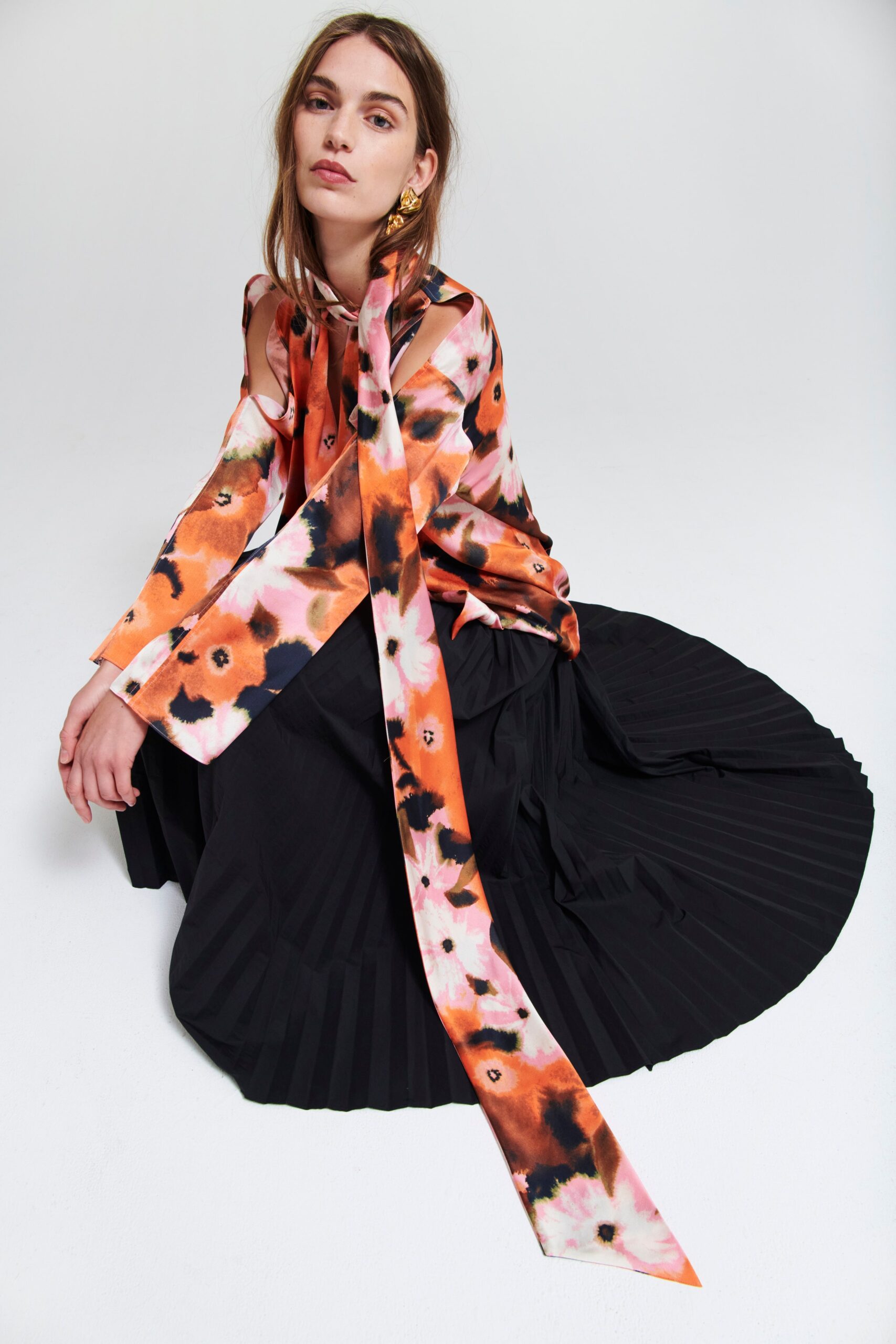 A relaxed black pleated skirt paired with a long-sleeve collared blouse in vibrant colors.