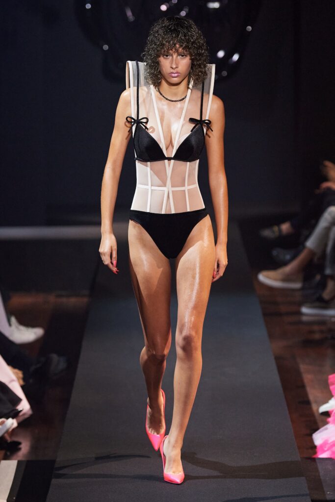 A fitted black and white sleeveless bodysuit with a V-neckline and asymmetric design.