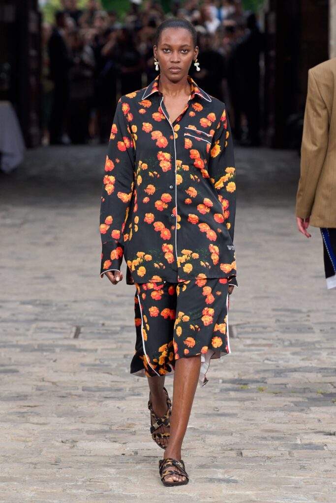 A relaxed black dress with long sleeves, a collared neckline, and a floral pattern.