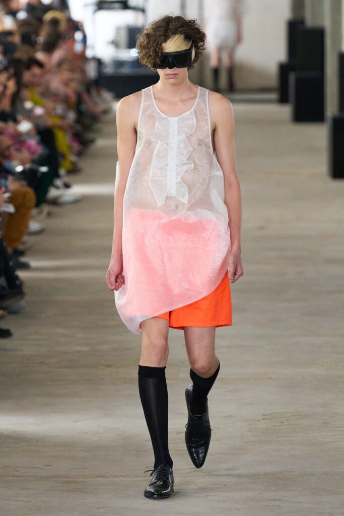 A relaxed pink sheer dress with an asymmetric design and V-neckline.
